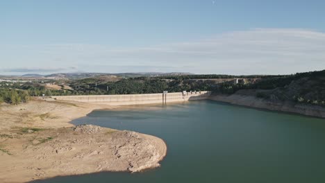 Vista-Aérea-De-Una-Presa-Hidroeléctrica-Al-Atardecer-Con-Bajo-Nivel-De-Agua-En-Verano