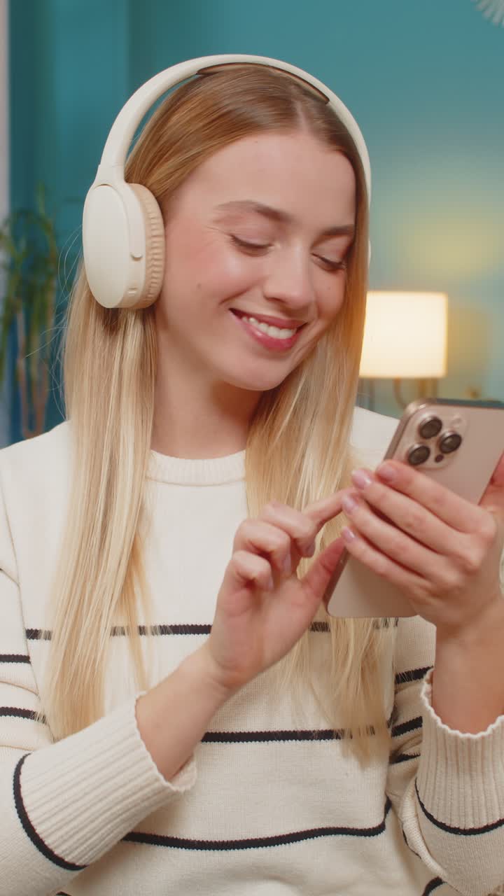 Donna caucasica che si rilassa sul divano ascoltando musica con le cuffie e lo smartphone in mano