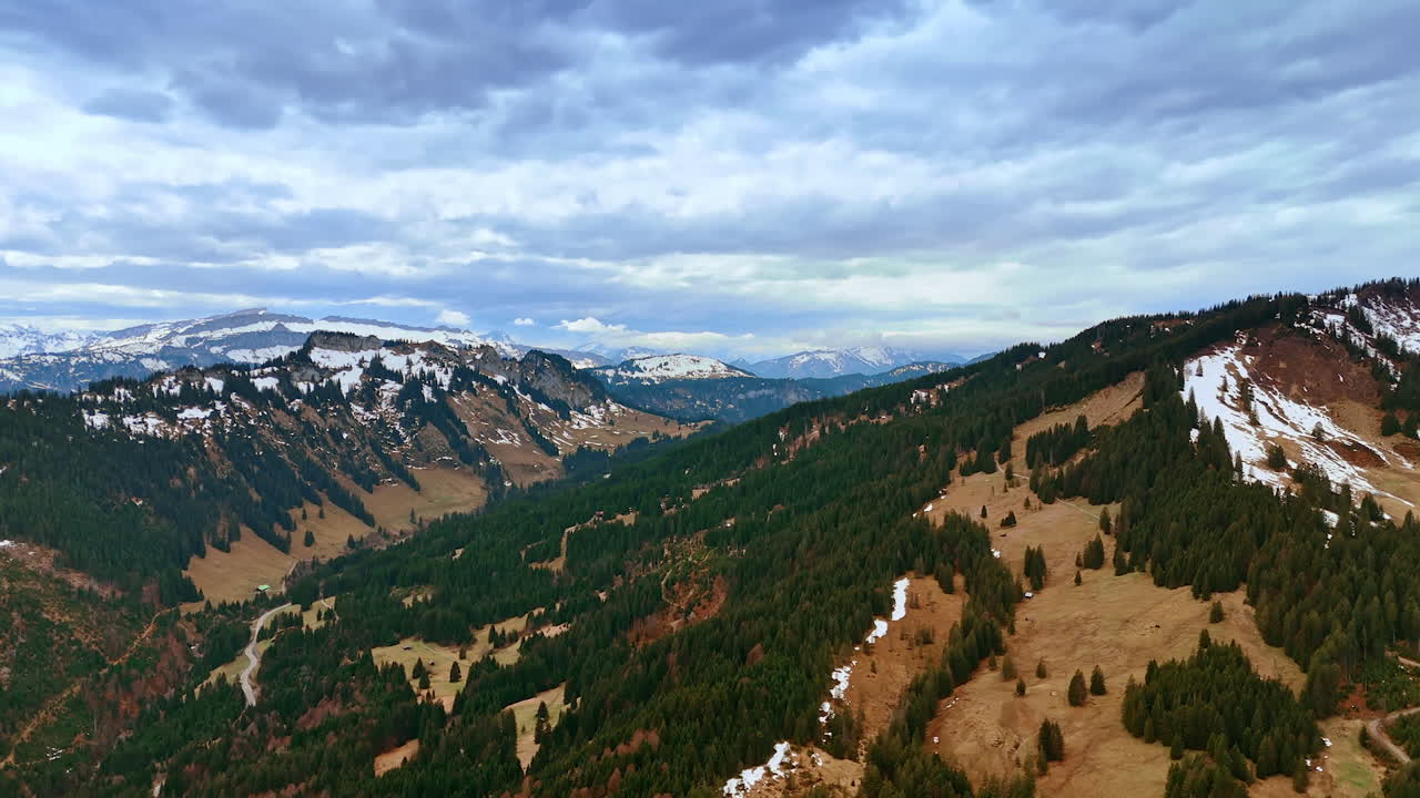 Idyllic view of the high mountains covered with green pine tree forests. Rocky landscape meeting cloudscape at the horizon. Aerial view.