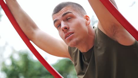 Exhausted-young-athletic-man-recovers-after-his-exercises-in-training-area-of-park