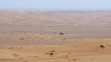 Landcruiser-De-Cuatro-Ruedas-Conduciendo-En-Un-Desierto-árido-Durante-El-Día-En-Sharjah,-Emiratos-Árabes-Unidos---Tiro-De-Seguimiento