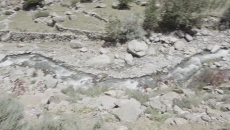 River-flow-through-sandy-and-rocky-landscape-of-Panshir-valley,-top-down-pan-right-view