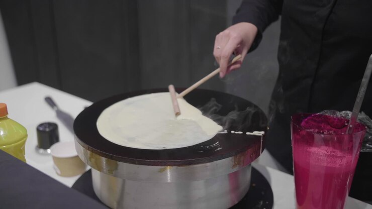 Donna che prepara delle crêpes in un mercato locale