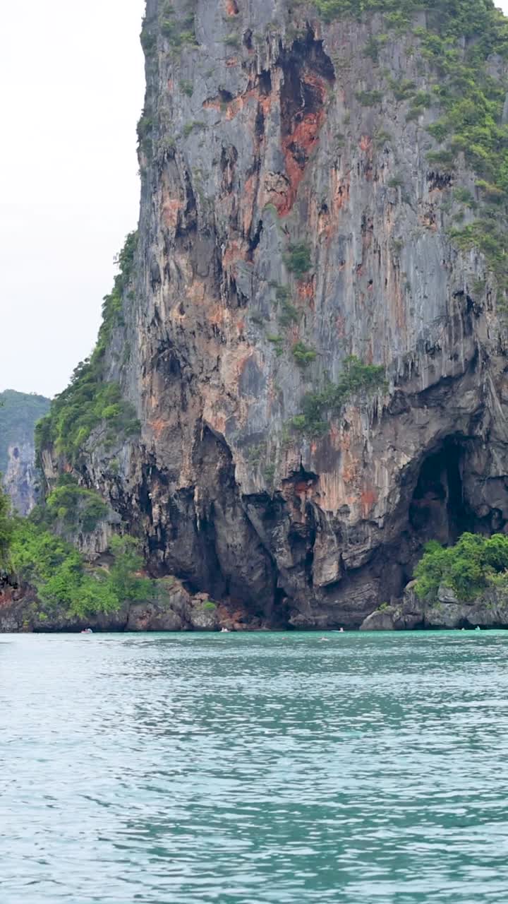 Una prospettiva verticale di maestose scogliere calcaree che si ergono da calme acque turchesi in Thailandia.