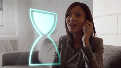 animación de icono de vidrio de hora de neón contra mujer de negocios biracial hablando en teléfono inteligente en la oficina