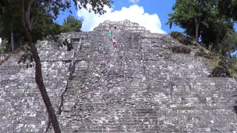 tourist climbing the temple 216 in the east acropolis at yaxha, guatemala