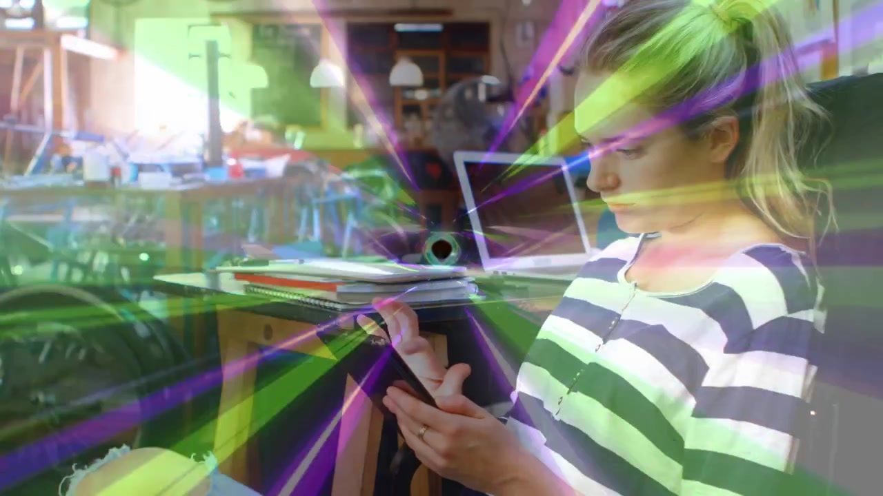 Mujer pulsando el teléfono en un escritorio de diseño, generando haces animados y un ojo central que revela un portátil y herramientas.