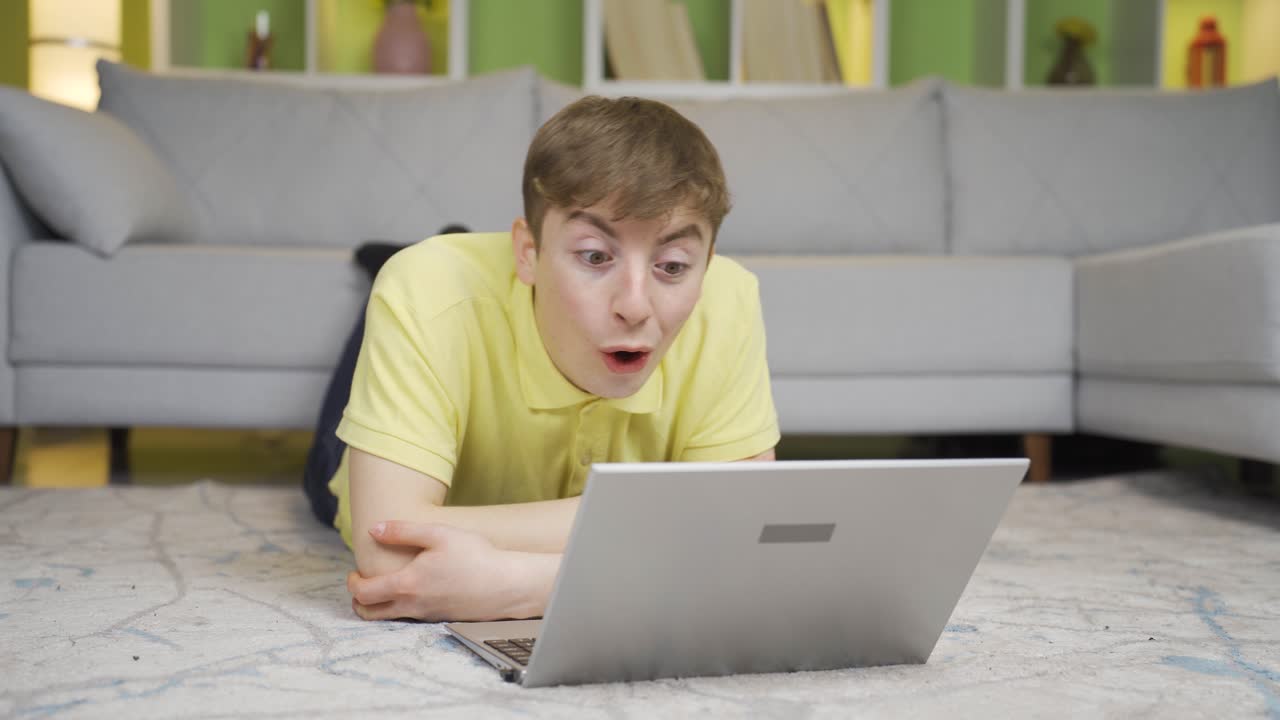 joven mirando la computadora portátil en casa dice wow, asombrado.