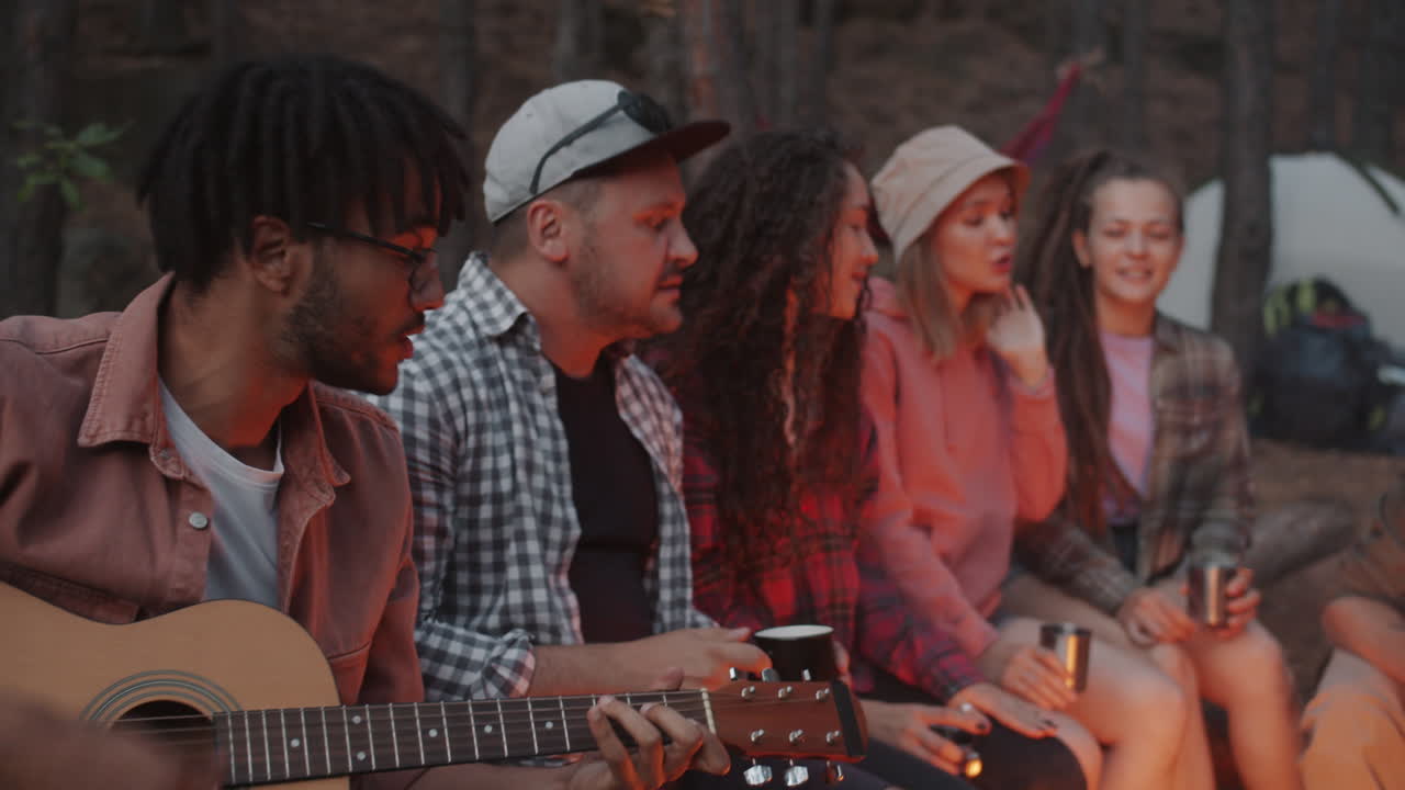Friends Enjoying Music Around Campfire