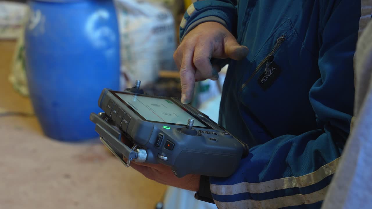 Close-up van een vuile boerenhand die de afstandsbediening van een drone verkent, terwijl hij leert hoe hij het systeem moet bedienen.