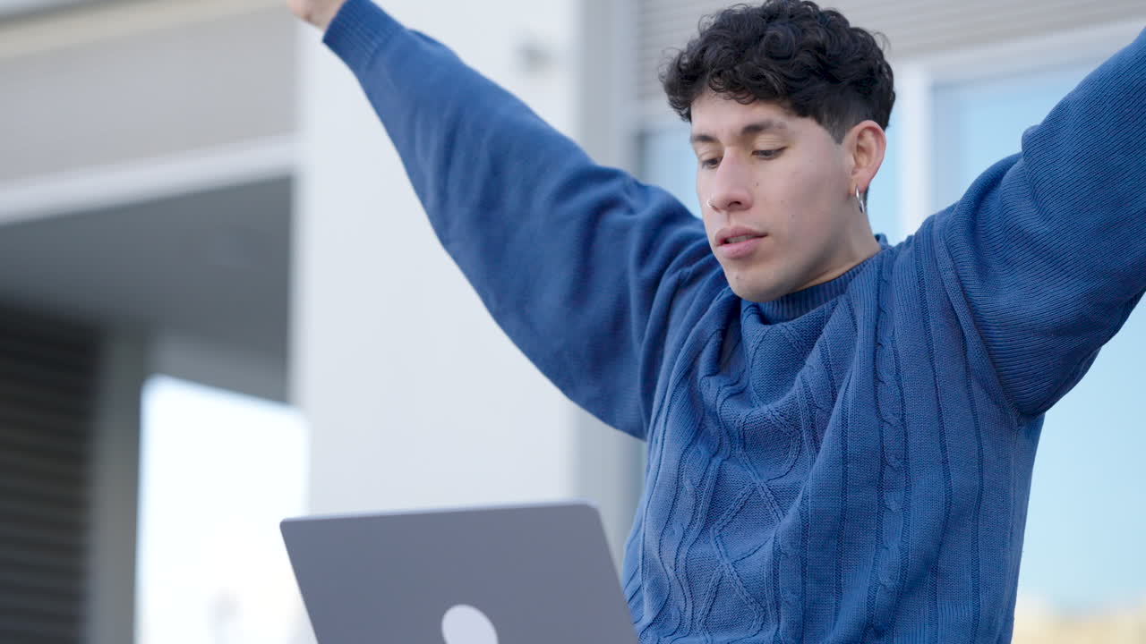 Student celebrating success on laptop outdoors
