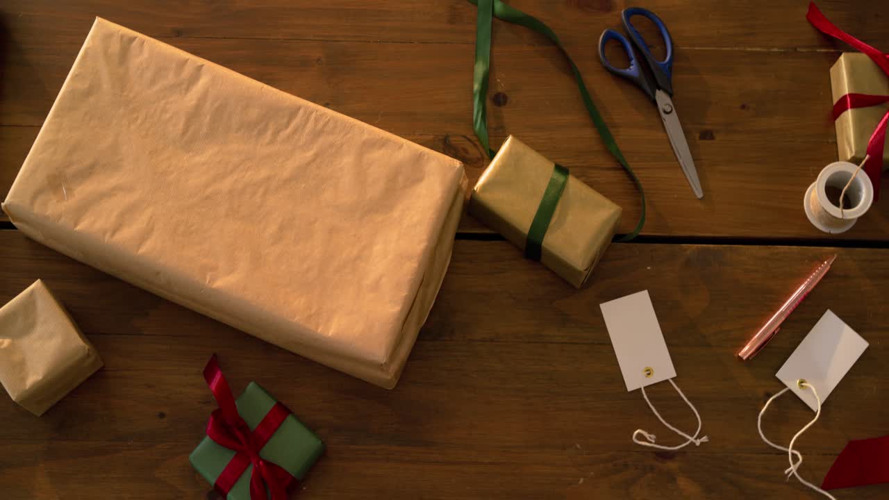 At start camera panning left-to-right over table, exposing gold-wrapped gifts and wrapping tools