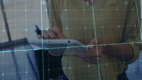 animation of grid network over mid section of a woman using digital tablet at office