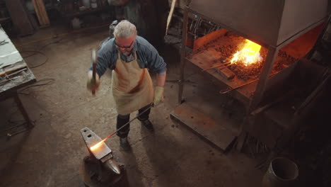 blacksmith hammering heated iron on anvil in forge