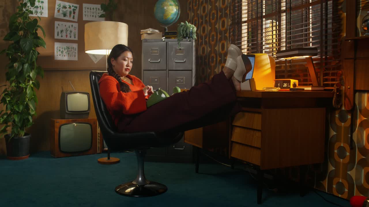 1960 년대 스타일의 사무실에서 레트로 전화로 이야기하는 여성