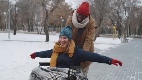 couple in park helping disabled person in wheelchair during winter