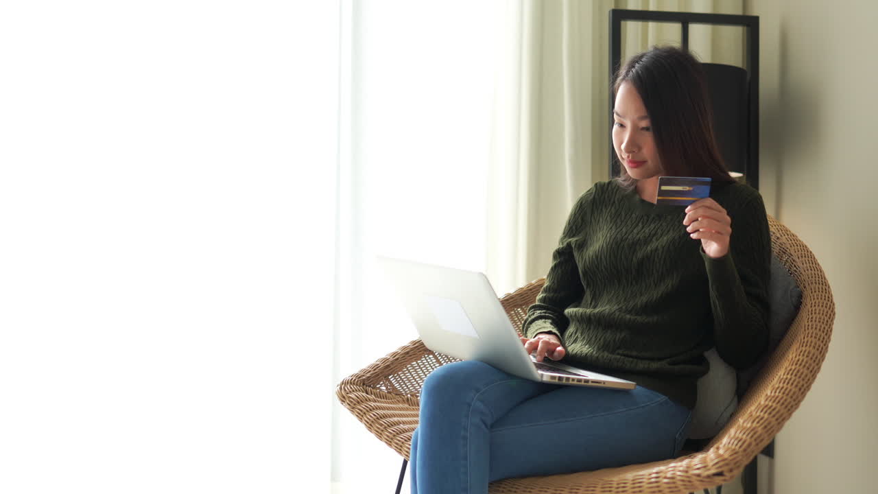 노트북에 신용카드 정보를 입력하는 젊은 아시아 여성