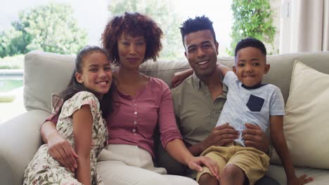 retrato de padres africanos americanos felices con un hijo y una hija, sentados en el sofá en casa