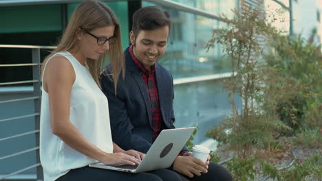 Smiling-business-people-talking-and-using-laptop