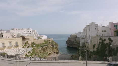 Luftaufnahmen-Fliegen-über-Eine-Brücke-Und-über-Lama-Monachile-In-Richtung-Meer-In-Polignano-A-Mare,-Italien