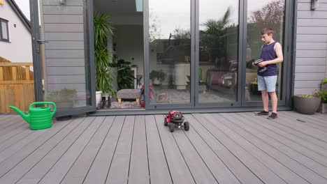 young boy at home outdoors in the garden playing with his rc car, truck, 4 x 4