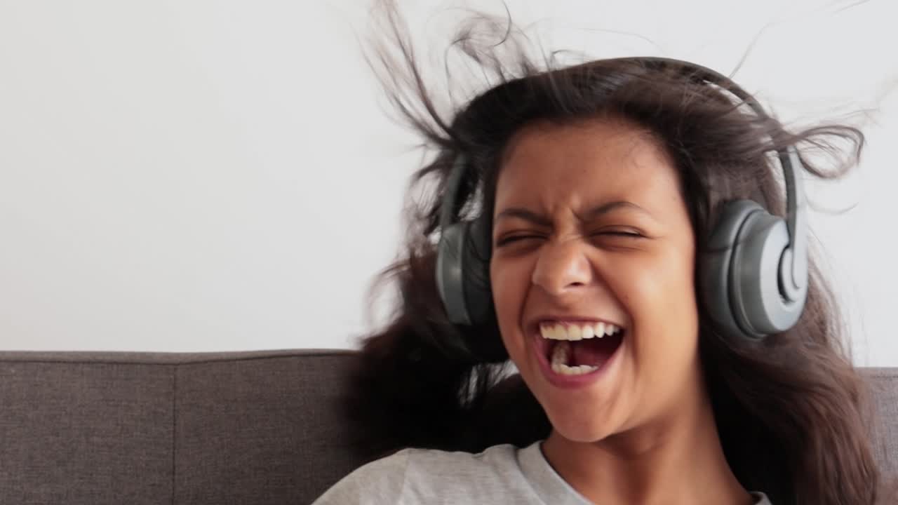 Excited Young Woman Laughing While Listening to Music with Headphones