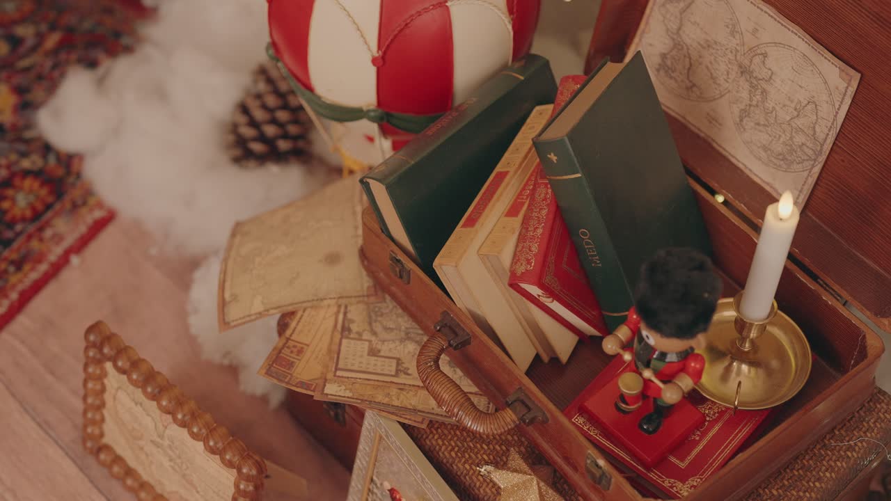 Old suitcase filled with books maps and candle beside festive decor