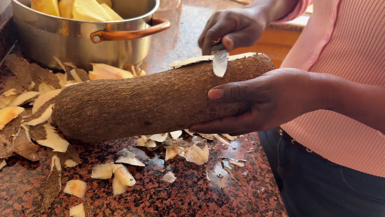 Vista ravvicinata delle mani di una donna africana che sbuccia un igname con un coltello su un tavolo di marmo