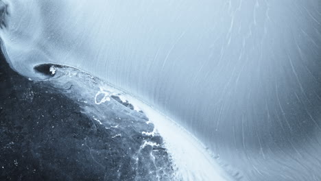 abstract texture of alcoholic ink forming smooth icy waves in soft blue tones