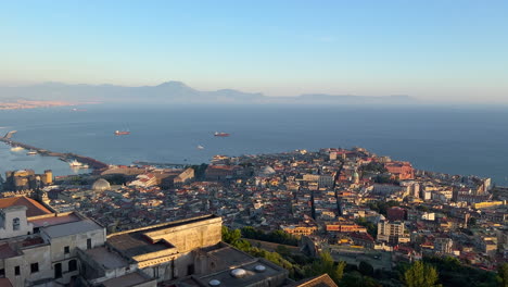 Erhöhter-Blick-Auf-Neapel-Mit-Schwerpunkt-Auf-Der-Dichten-Architektur-Der-Stadt,-Der-Küste-Und-Dem-Glitzernden-Mittelmeer-Bei-Sonnenaufgang