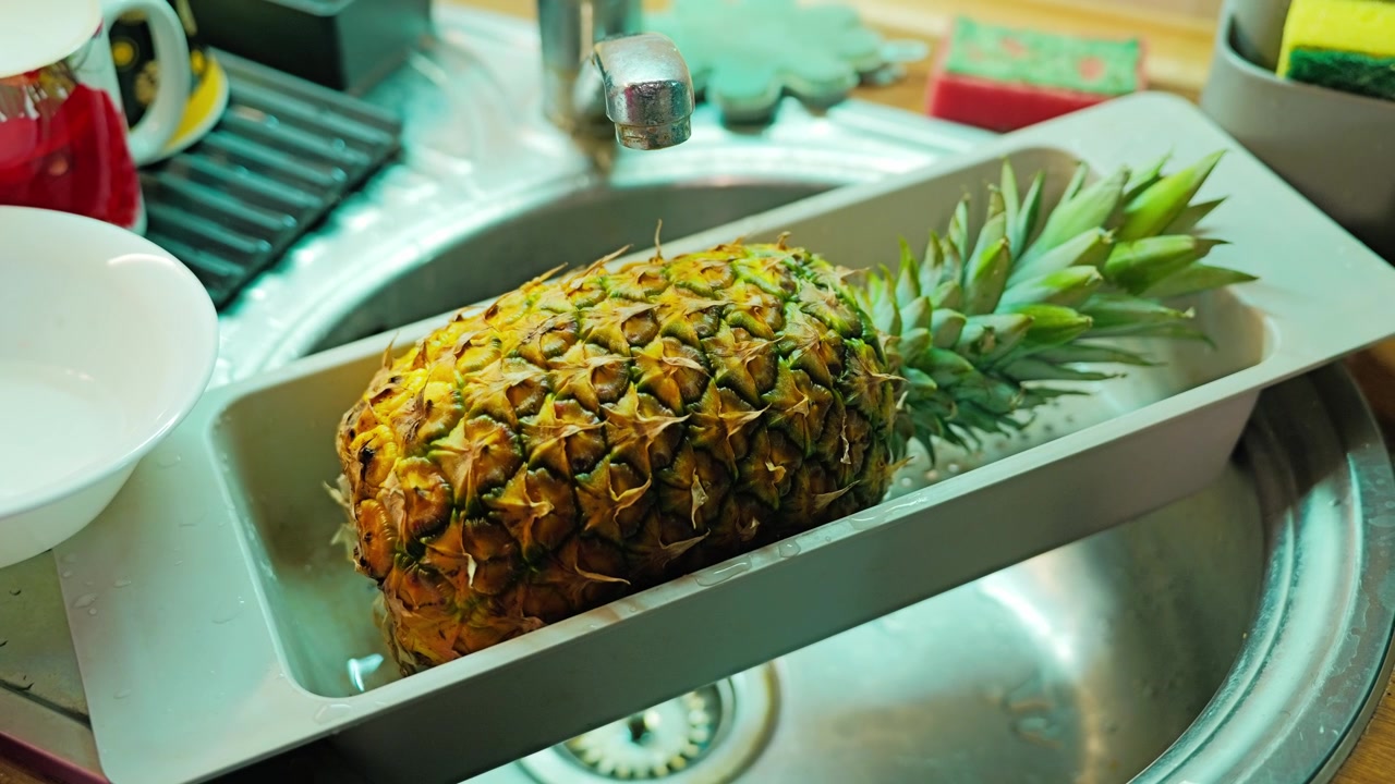 Freshly washed pineapple dries beside the sink before cutting and serving
