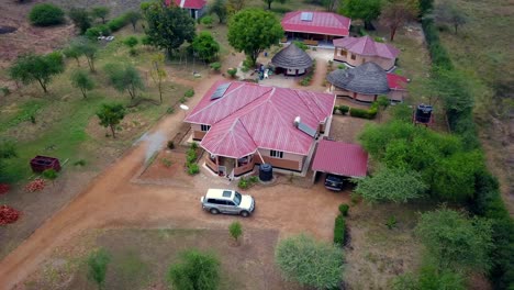 Capturing an aerial view of a vocational school in Matany, Moroto, Uganda, blending traditional and modern architecture with solar panels and a scenic landscape, drone establishing shot