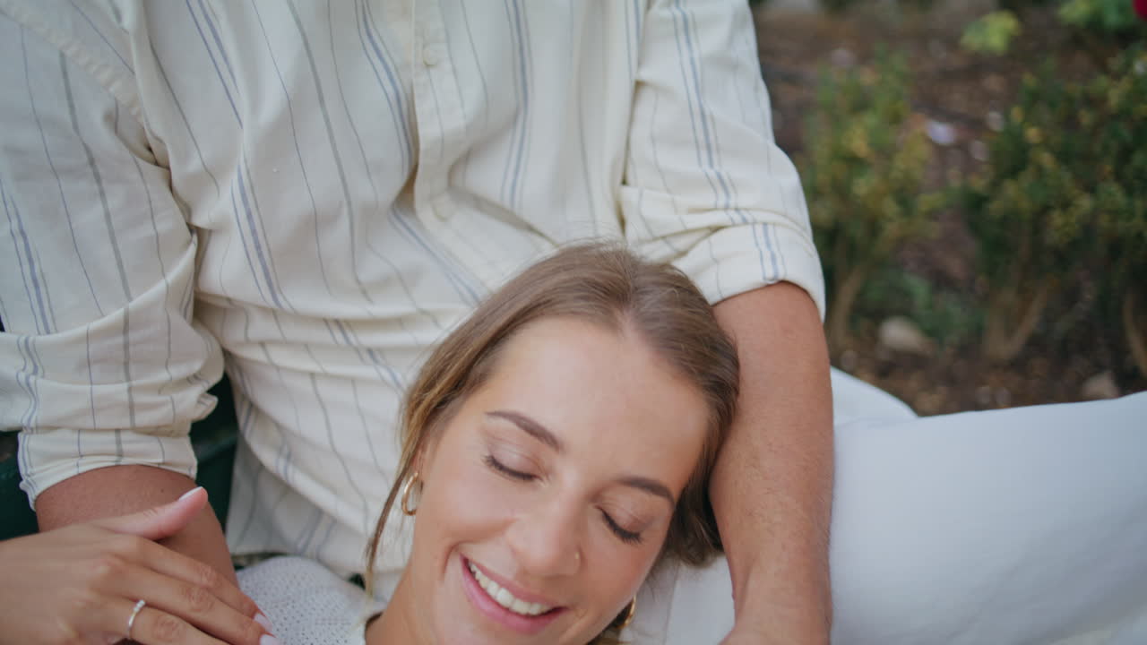 웃는 여자친구가 벤치에 앉아 있는 남자와 함께 책을 즐기고 있다. 마초가 큰 소리로 읽고 있다.