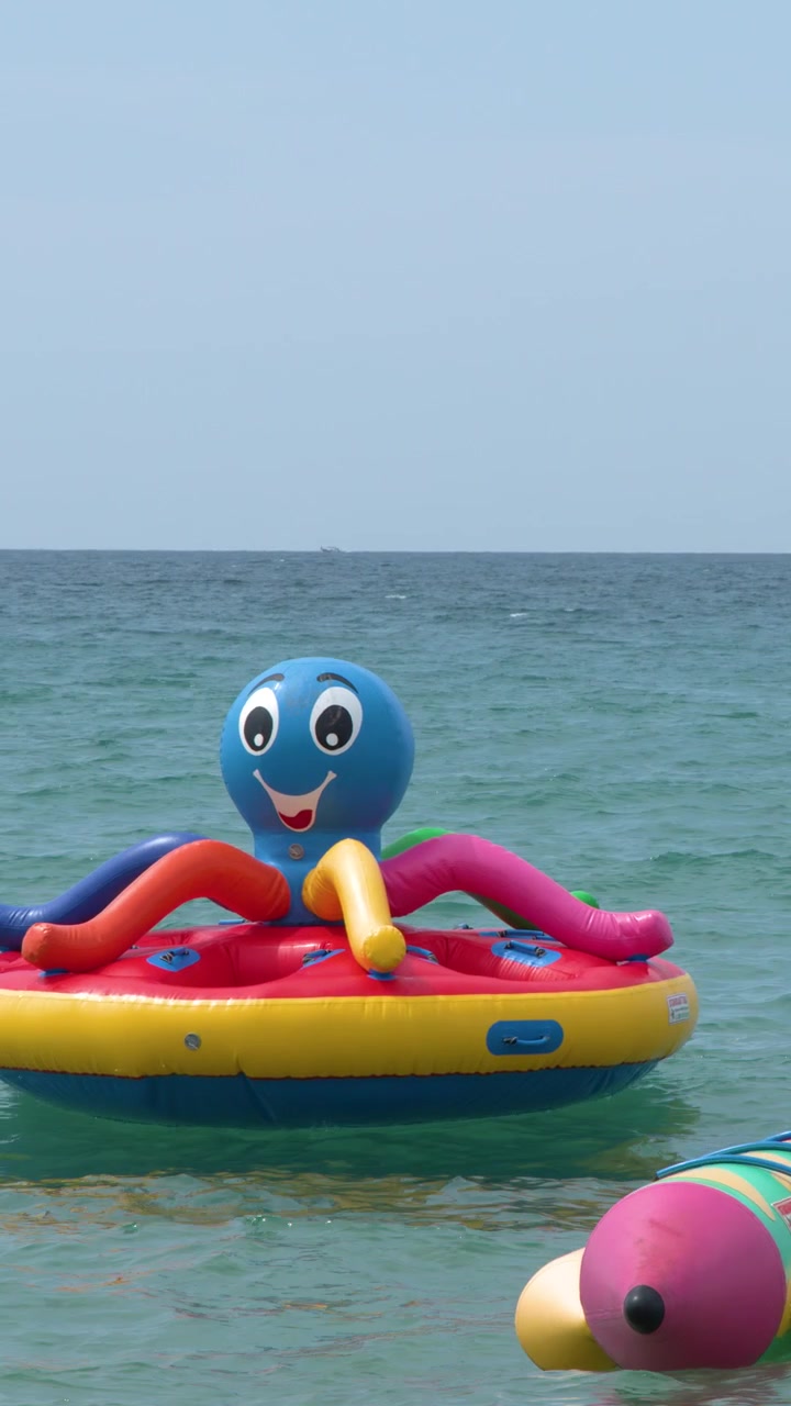 Vibrant inflatable watercraft float on calm turquoise ocean water under a clear blue sky