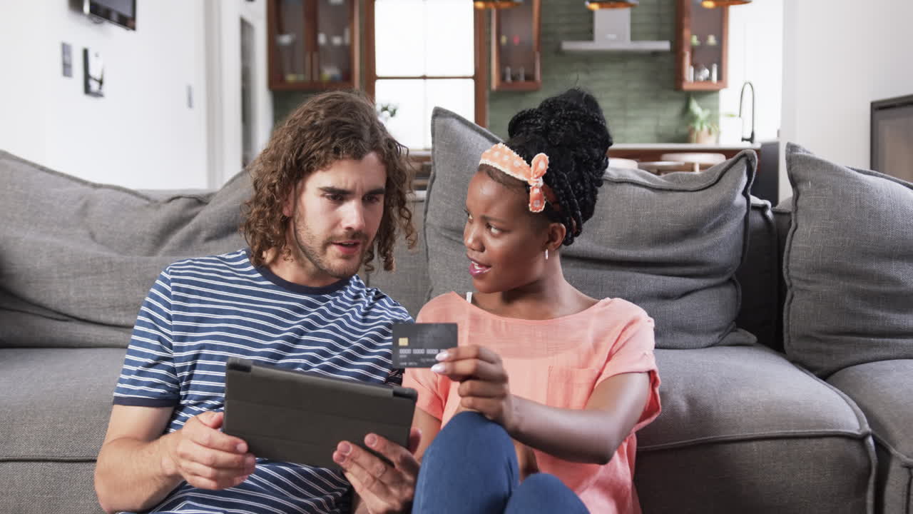 Diverse couple: a young African American woman and Caucasian man shopping online at home