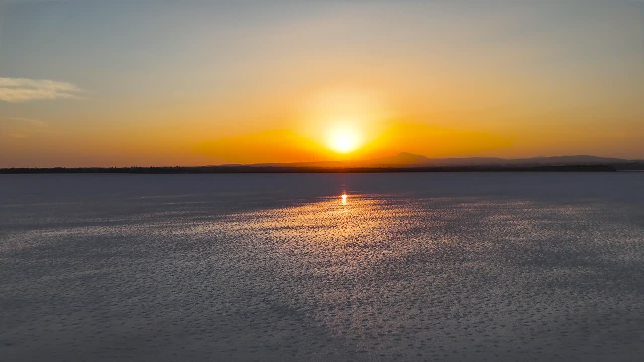 Sunset over a calm lake with mountains in the background
