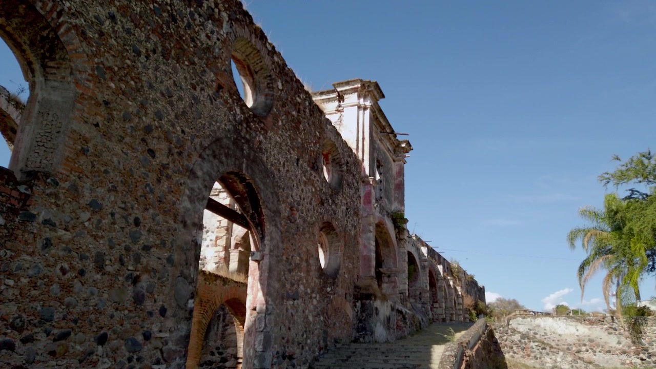 Ruínas históricas da Fazenda Coahuixtla em Morelos, México, apresentando paredes de pedra desgastadas, janelas em arco e arquitetura colonial, refletindo herança cultural e história.
