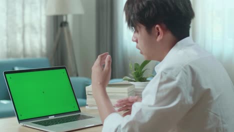 close up of asian man student being tired while looking at green screen computer at home