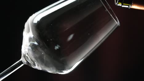 Super-slow-motion-of-Red-wine-poured-into-a-wine-glass-in-Black-background,-Close-up-shot