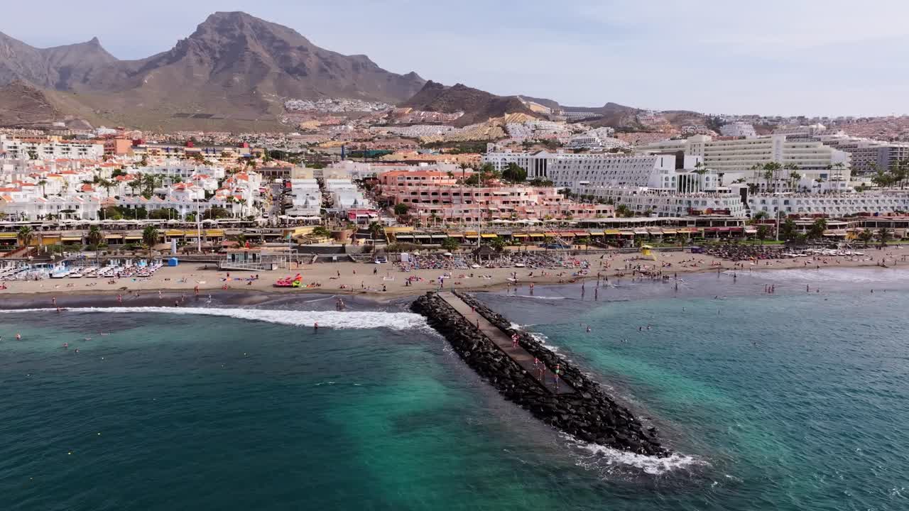 Aerial view of a beach with buildings and a mountain in the background