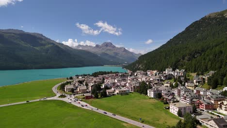 aerial view of a road with traffic winding through the residential area near lake silvaplanersee in silvaplana, graubünden, switzerland, capturing the blend of natural beauty and human activity.