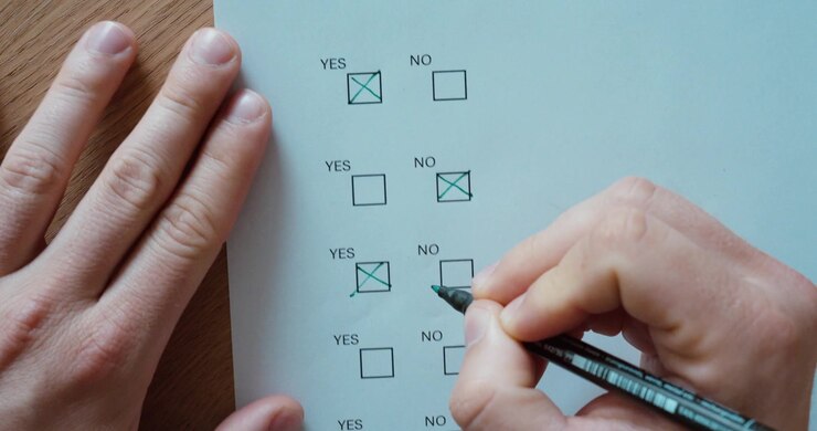 Primo piano di una persona che seleziona l'opzione "Sì" su un questionario o modulo di sondaggio. Concetto di processo decisionale, voto, approvazione, feedback e completamento moduli.