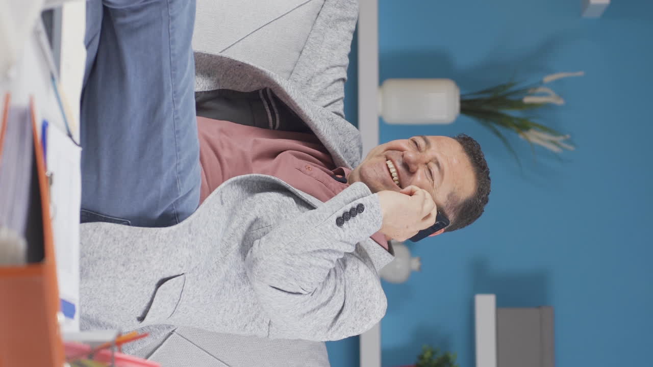 홈 오피스 직원 노인이 행복하게 전화로 이야기하는 수직 비디오.