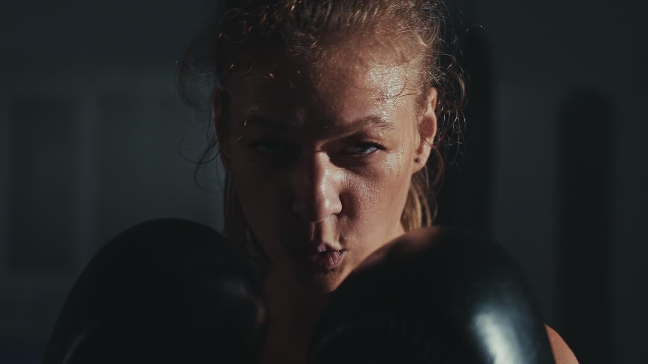 Intense Female Boxer with Sweaty Face and Gloves in Gym