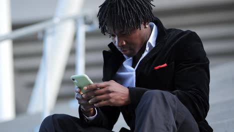 young african businessman in a black suit, taking a call on stairs