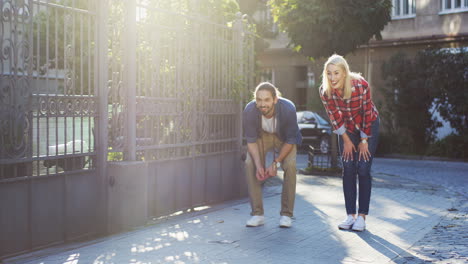 Pareja-Joven-Parada-En-La-Calle-Y-Su-Perro-Labrador-Corriendo-Hacia-Ellos-En-Un-Día-Soleado