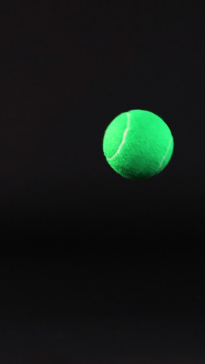 Tennis ball bouncing against a dark background