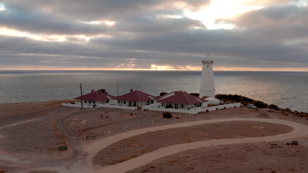 Aerial view of Cape Willoughby Lighthouse and cottages under a dramatic cloudy sunrise sky, Kangaroo Island, South Australia