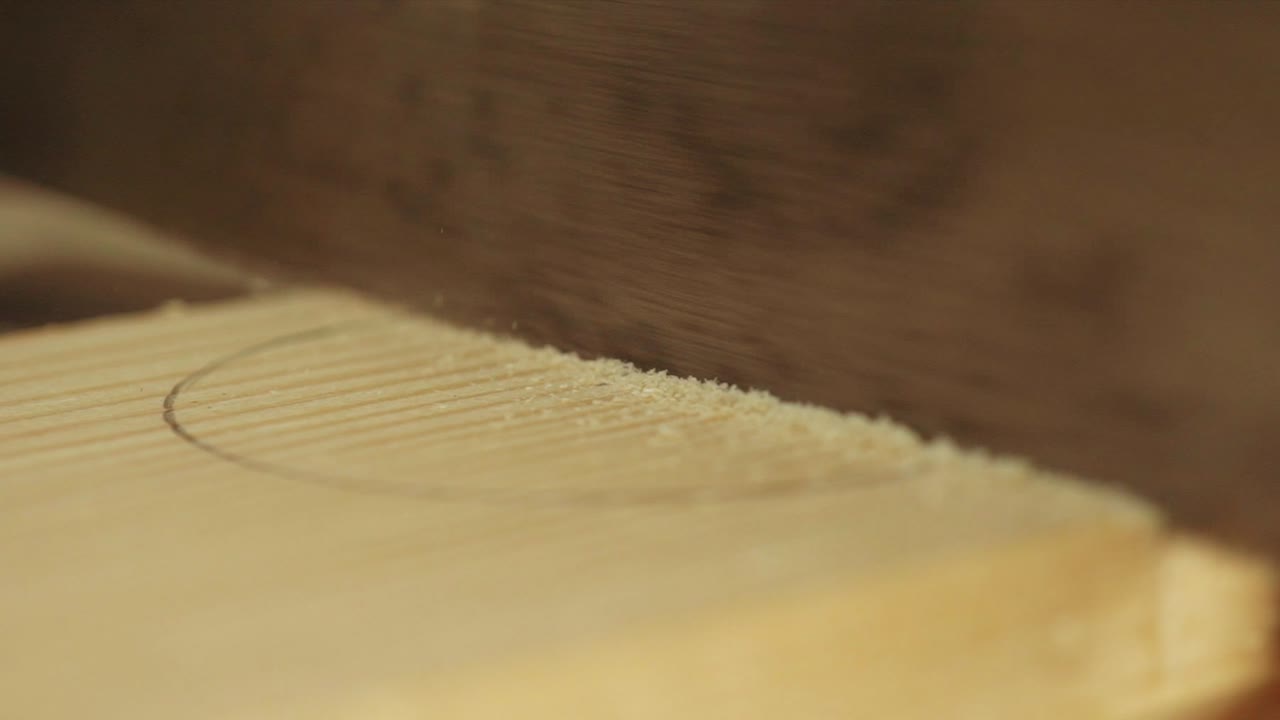 가구 작업장에서 느린 동작으로 목재 조각을 톱질하는 장부 톱날의 매크로 샷