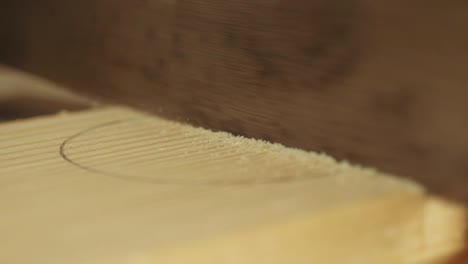 a macro shot of a tenon saw blade sawing a piece of timber in a furniture workshop in slow motion